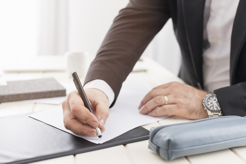 Homme écrivant document sur bureau